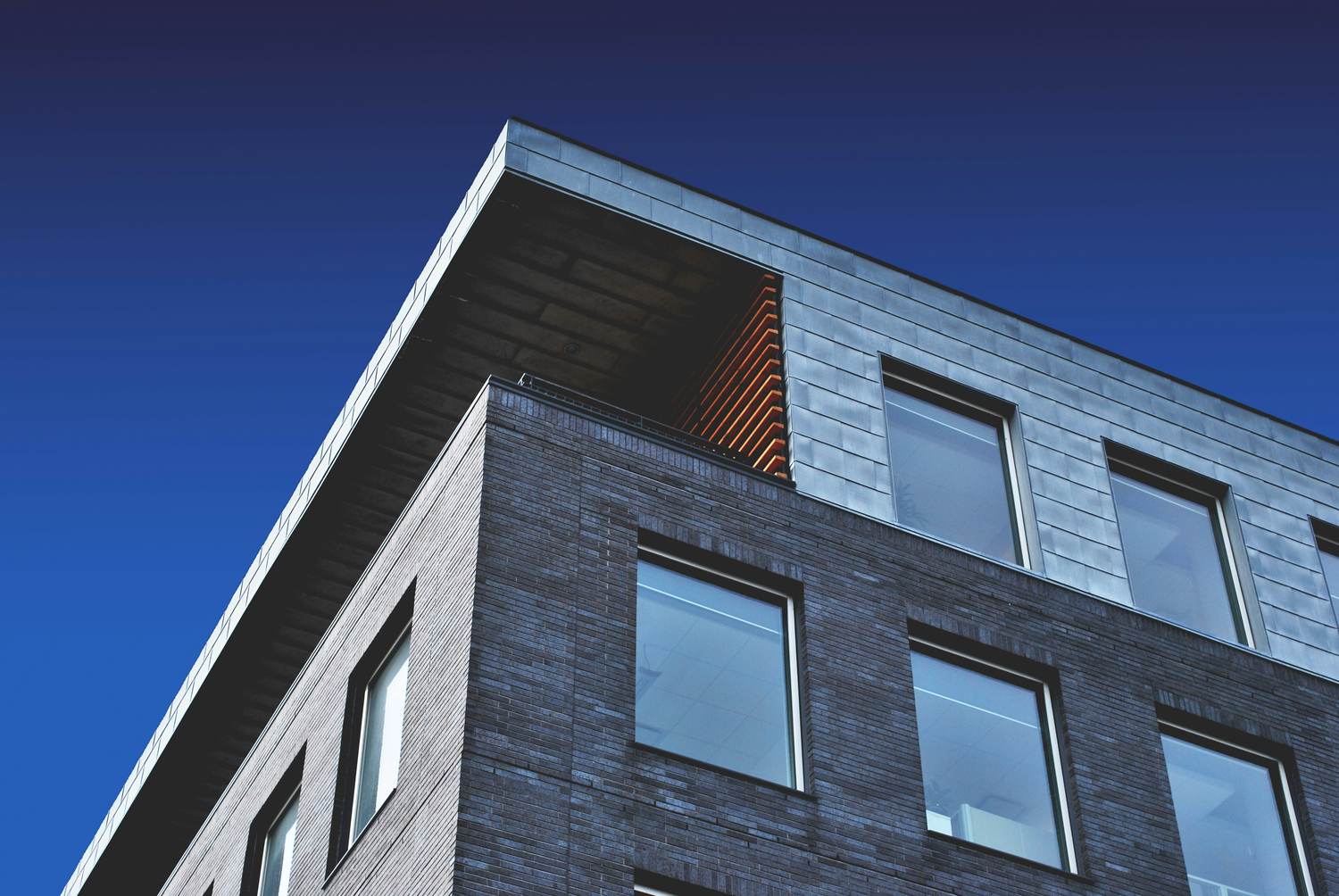 Modern brick and metal building against a deep blue sky